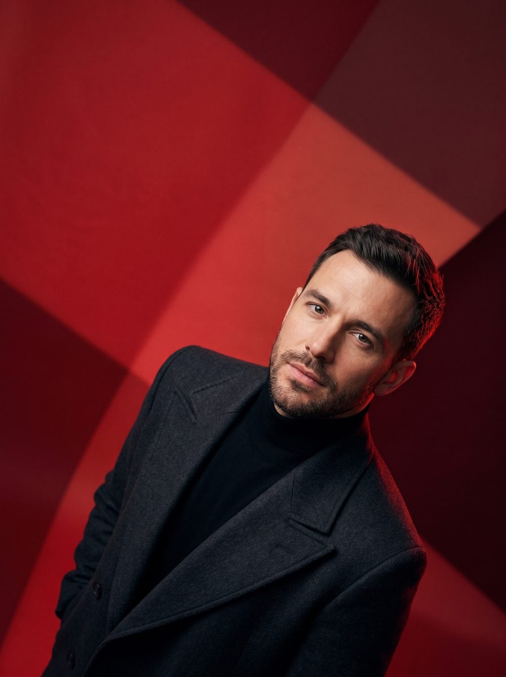 Man in a dark suit and turtleneck poses against a red geometric backdrop, created with an AI Prompt for ChatGPT and Gemini.
